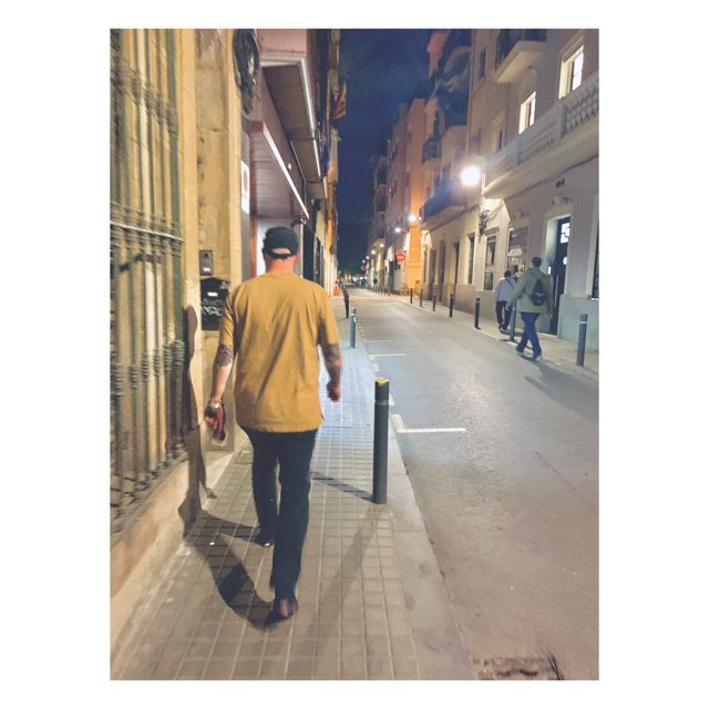 Picture of Kevin Duffy from the back, walking on the sidewalk at night in Barcelona